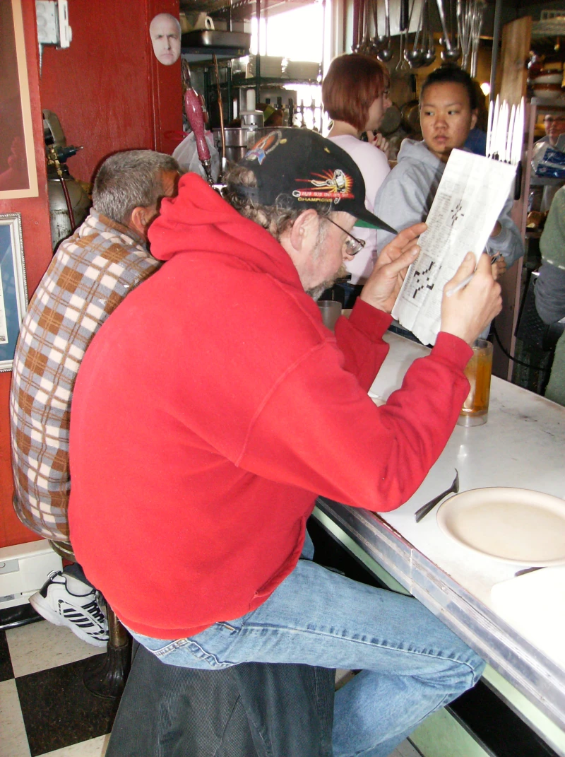 Person solving a crossword puzzle with a pen